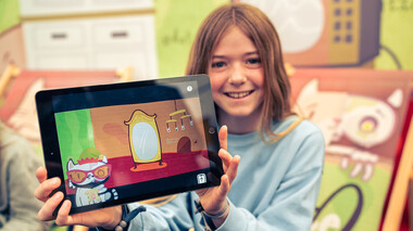 Mädchen präsentiert Tablet mit der Katze-Q-App, Foto: Tobias Ritz.